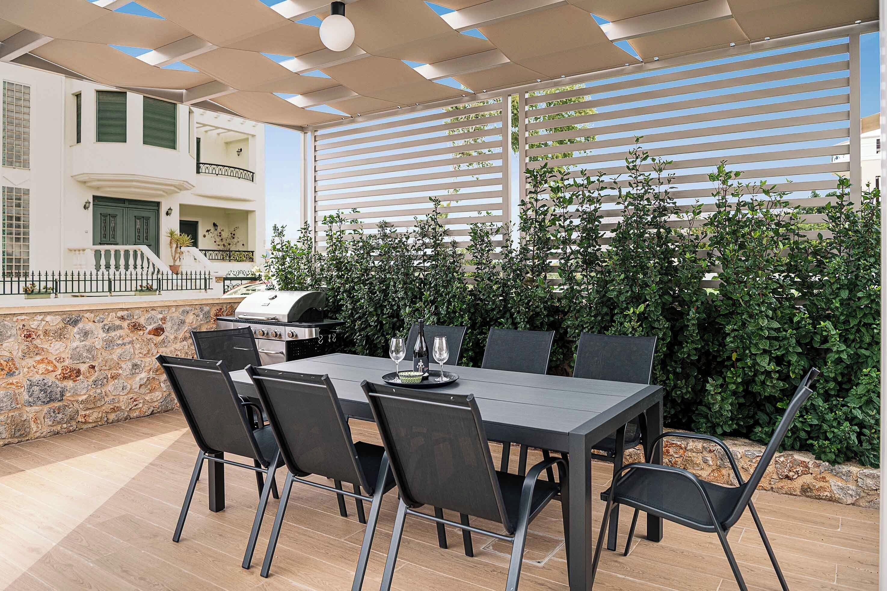 Un espacio de comedor al aire libre con una mesa, sillas, una parrilla y un muro de piedra.