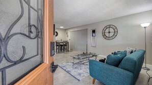 Una sala de estar con un sofá azul, una mesa de centro y un reloj de pared.