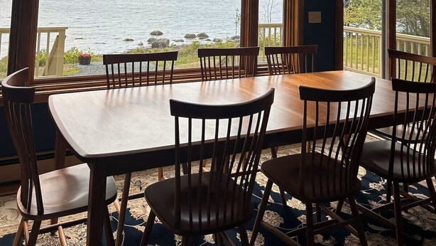 A dining area with a view of a lake, a chandelier, and wooden furniture. - Bayberry  (Trenton)