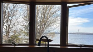 A kitchen with a window overlooking a body of water and trees. - Bayberry  (Trenton)