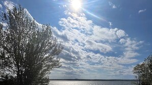 A wooden deck with a railing, a potted plant, and a view of a body of water under a clear sky. - Bayberry  (Trenton)