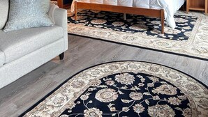A bedroom with a wooden bed, a grey sofa, and a large rug. - Bayberry  (Trenton)