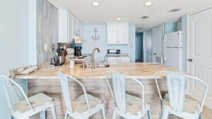Una cocina amplia con una isla central, armarios blancos y un ancla decorativa en la pared.