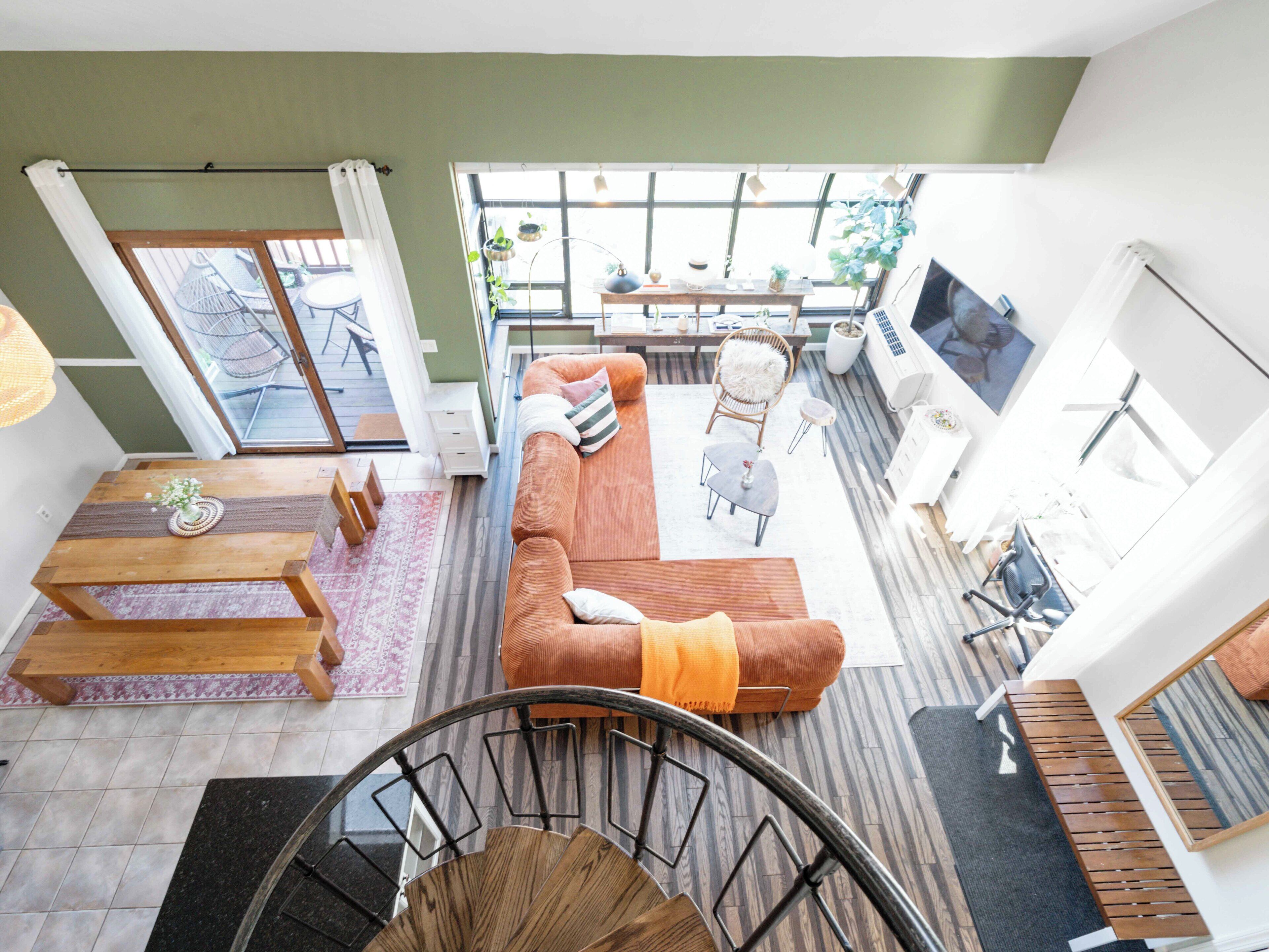 Un amplio espacio de sala con un sofá grande, una mesa de comedor y una escalera que sube a otro nivel.