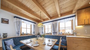 Uma área de jantar acolhedora, com uma mesa de madeira, bancos estofados em azul e um lustre.