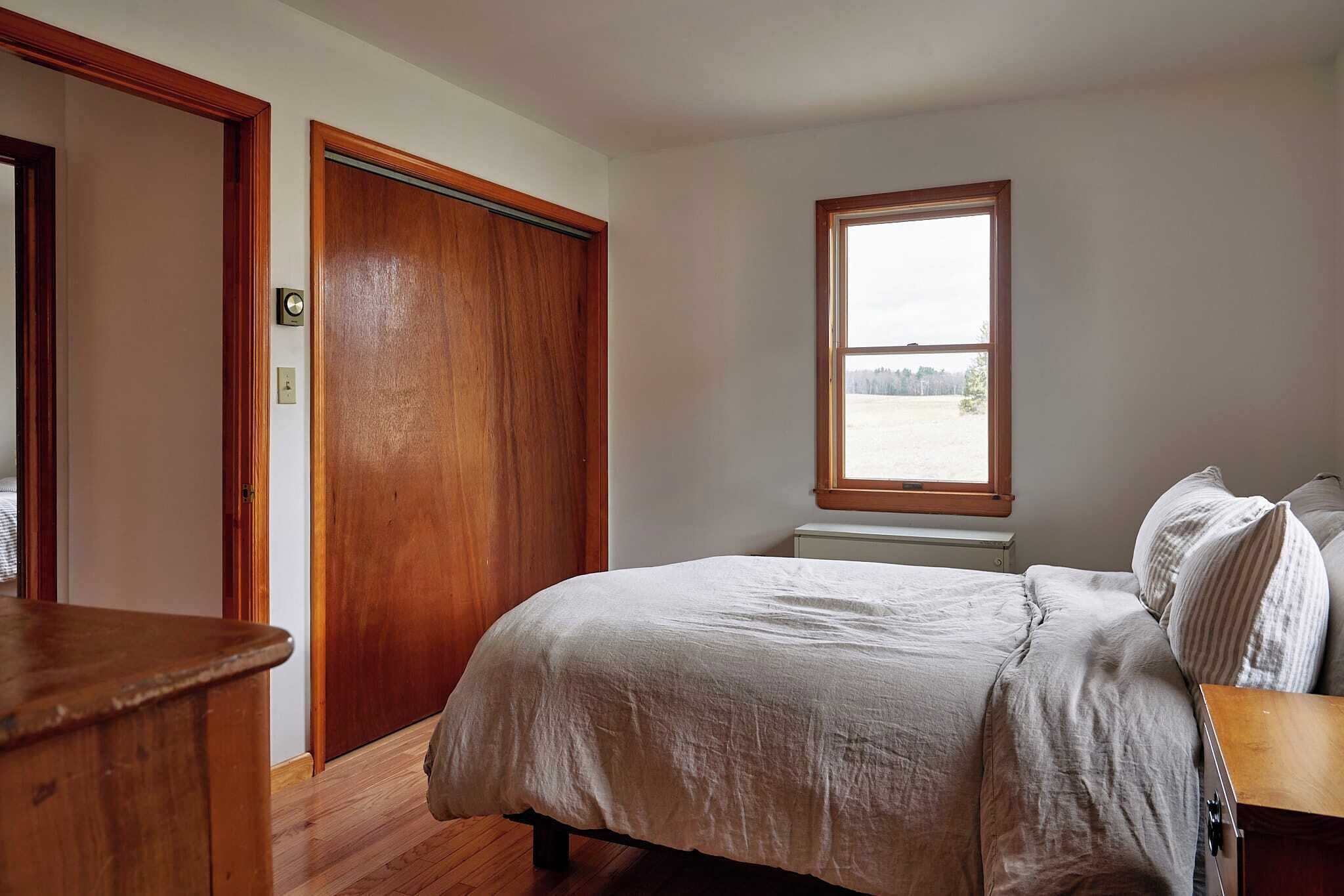 Una camera da letto con un letto, una finestra e una porta in legno.