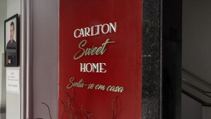 A red banner with the text "CARLTON Sweet HOME" and "Sunta-se em casa" on a wall. - Hotel Carlton Imbiara Express (Araxá)