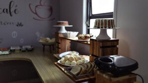 A wooden counter with a tray of bread, a cake on a stand, and a coffee machine. - Hotel Carlton Imbiara Express (Araxá)