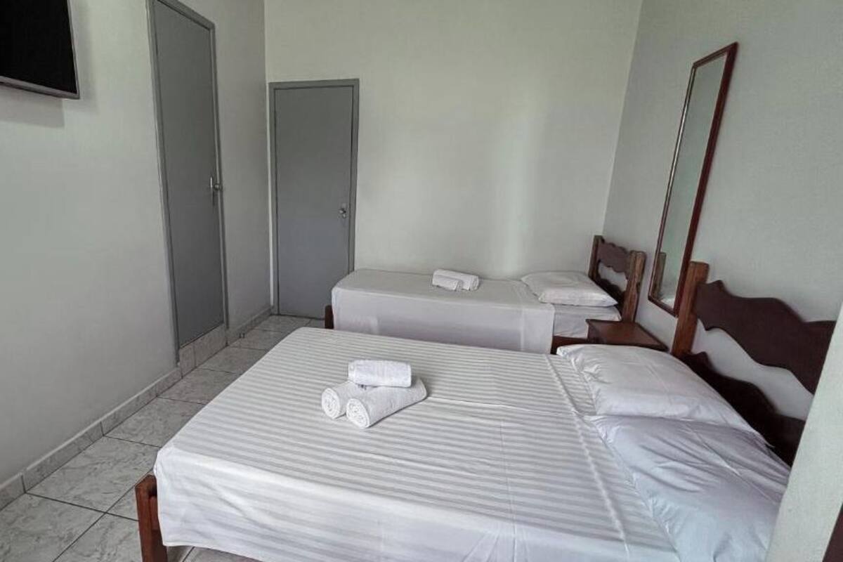 A hotel room with two beds, a flat-screen TV, a door, and a mirror.