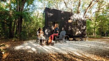 A small cabin with a fire pit and a bench outside.