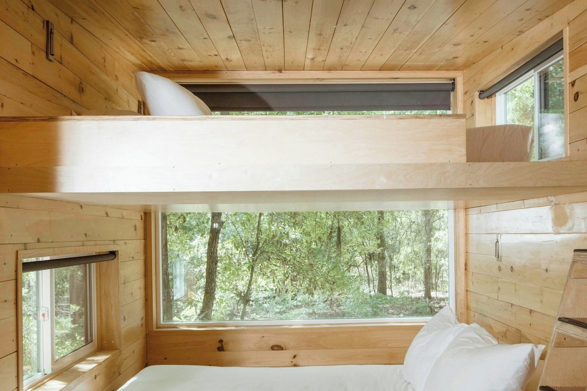 Une chambre avec un lit superposé et une fenêtre donnant sur une forêt.