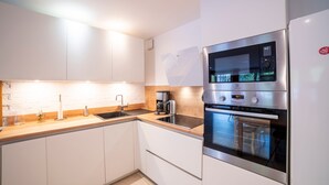 Una cocina moderna con armarios blancos, un horno de acero inoxidable y un microondas integrado.