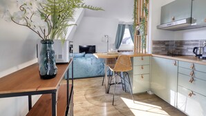 Et moderne køkken med spiseplads, en sofa og et stort vindue med gardiner.
