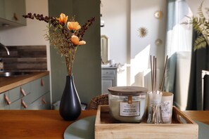 Un vassoio di legno con una candela, un diffusore di rattan e un vaso con fiori secchi su un tavolo.