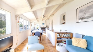 Ein geräumiger Wohnbereich mit Esstisch, blauem Sofa und Bücherregal.