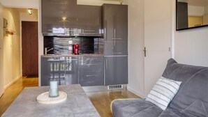 A modern kitchen with grey cabinets, a built-in oven, and a red coffee machine. - L'Estran - Appt 2p, proche de la mer (Villers-sur-Mer)