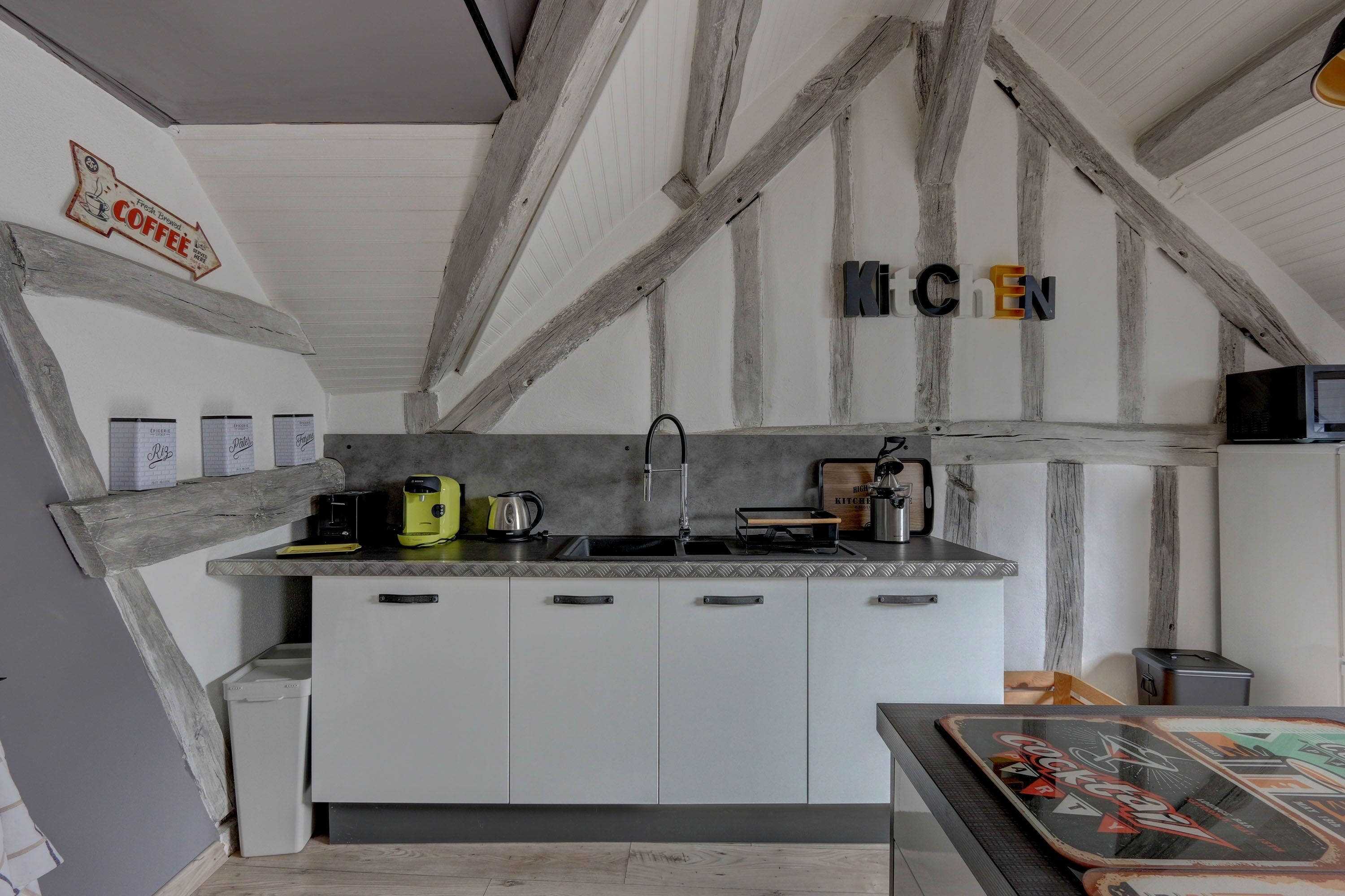 A kitchen with exposed wooden beams, a coffee sign, and a 'KITCHEN' sign.