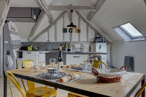 A dining area with a wooden table, yellow chairs, and a kitchen in the background. - Le Rabelais - Appt, à 5min du château d'Amboise (Amboise)