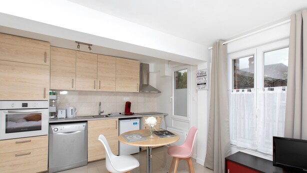 Una cocina moderna con armarios de madera, lavavajillas, estufa y un comedor con dos sillas y una mesa.