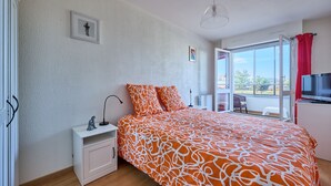 Une chambre avec un grand lit, une table de chevet, une télévision et une vue sur l’extérieur.