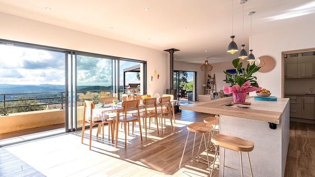 Una cocina moderna con una isla grande, suelo de madera y vistas al exterior.