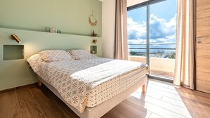 Un dormitorio con cama, vistas al mar, una puerta de madera y una pared verde.