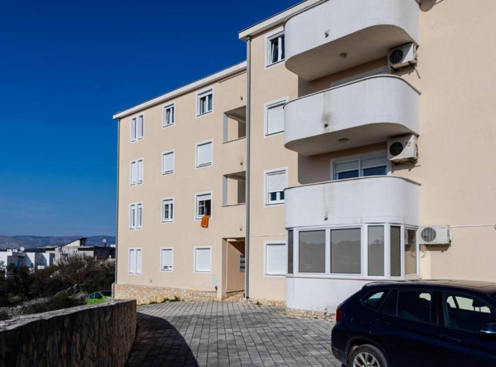 Un edificio residencial de varios pisos con fachada color beige, varias ventanas y balcones.