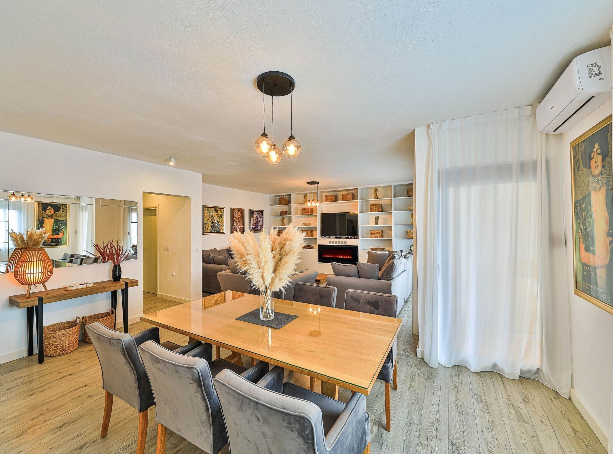 Un salon moderne avec une table à manger en bois, des canapés gris et une cheminée.