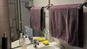 Ein Badezimmer mit einem weißen Waschbecken, einem Spiegel und einer Duschkabine.