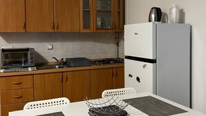 Eine kleine Küche mit Holzschränken, einer eingebauten Mikrowelle, einem Gasherd und einem weißen Kühlschrank.