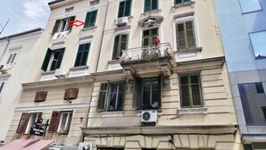 A multi-story building with a balcony on the second floor, a sign for a restaurant, and a row of windows with shutters.