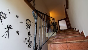A staircase with a metal railing and a wall decorated with various items including a clock, stars, and a camera. - Four Bedroom Holiday Home (Rijeka)
