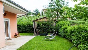 A well-maintained garden with a patio area, a pergola, and a wheelbarrow with flowers. - Four Bedroom Holiday Home (Rijeka)
