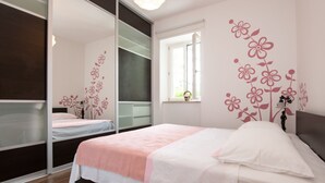 A bedroom with a bed, a window, and a mirror.