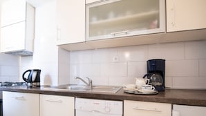A modern kitchen with white cabinets, a Bosch dishwasher, a coffee maker, and a kettle.