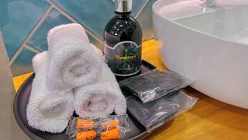 A bathroom with a white sink, a bottle of hand soap, a white towel, and a tray with toiletries.