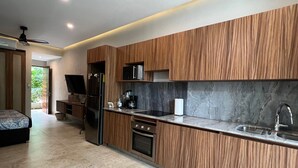 A modern kitchen with wooden cabinets, a marble countertop, and stainless steel appliances. - Charming Ocean line studio with largest pool in beautiful Troncones (Troncones)