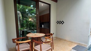 A small patio with a wooden table and chairs, a glass door leading to a pool area, and a tiled floor. - Charming Ocean line studio with largest pool in beautiful Troncones (Troncones)