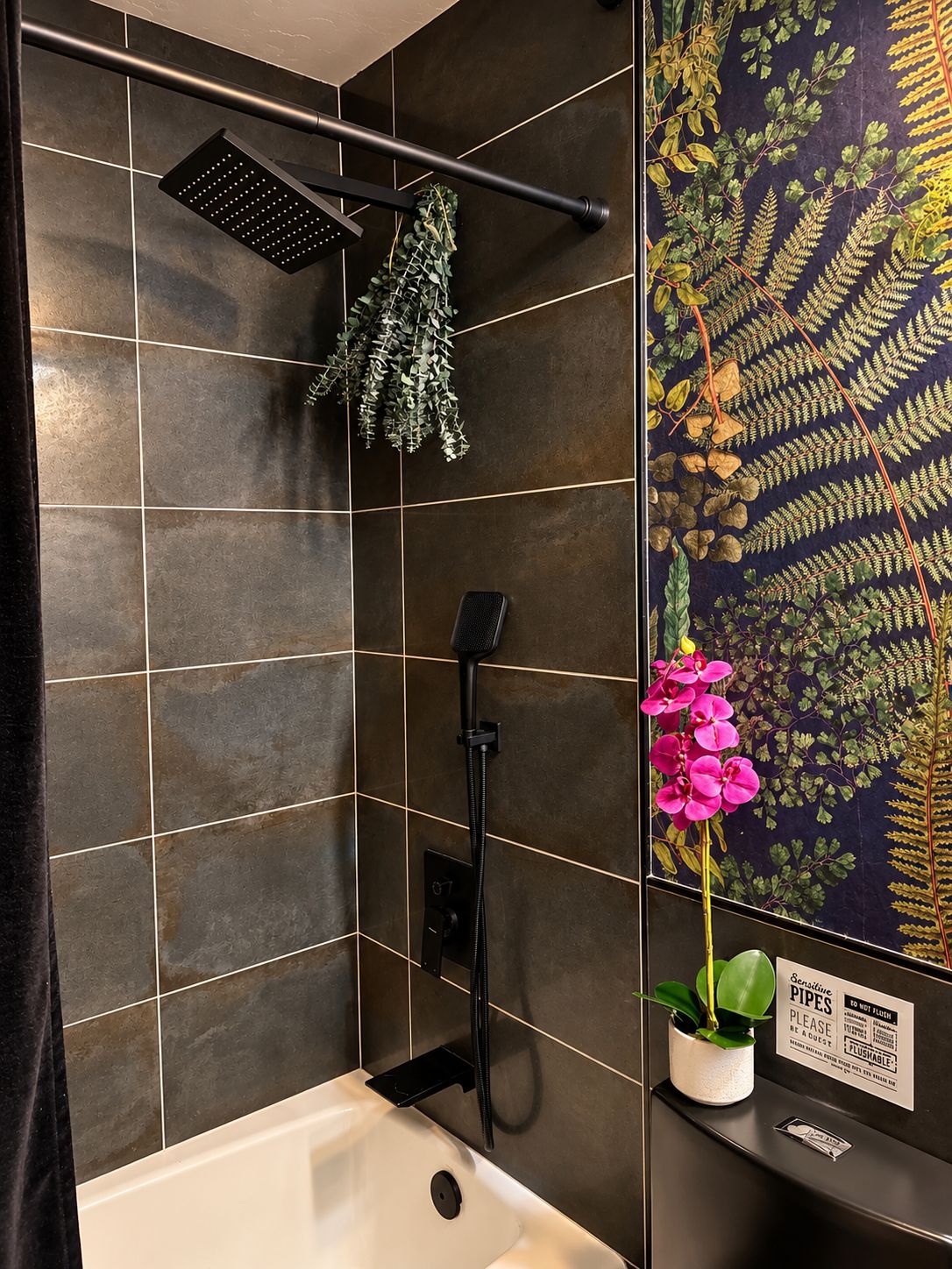A bathroom with a shower, a sink, and a decorative fern wall.