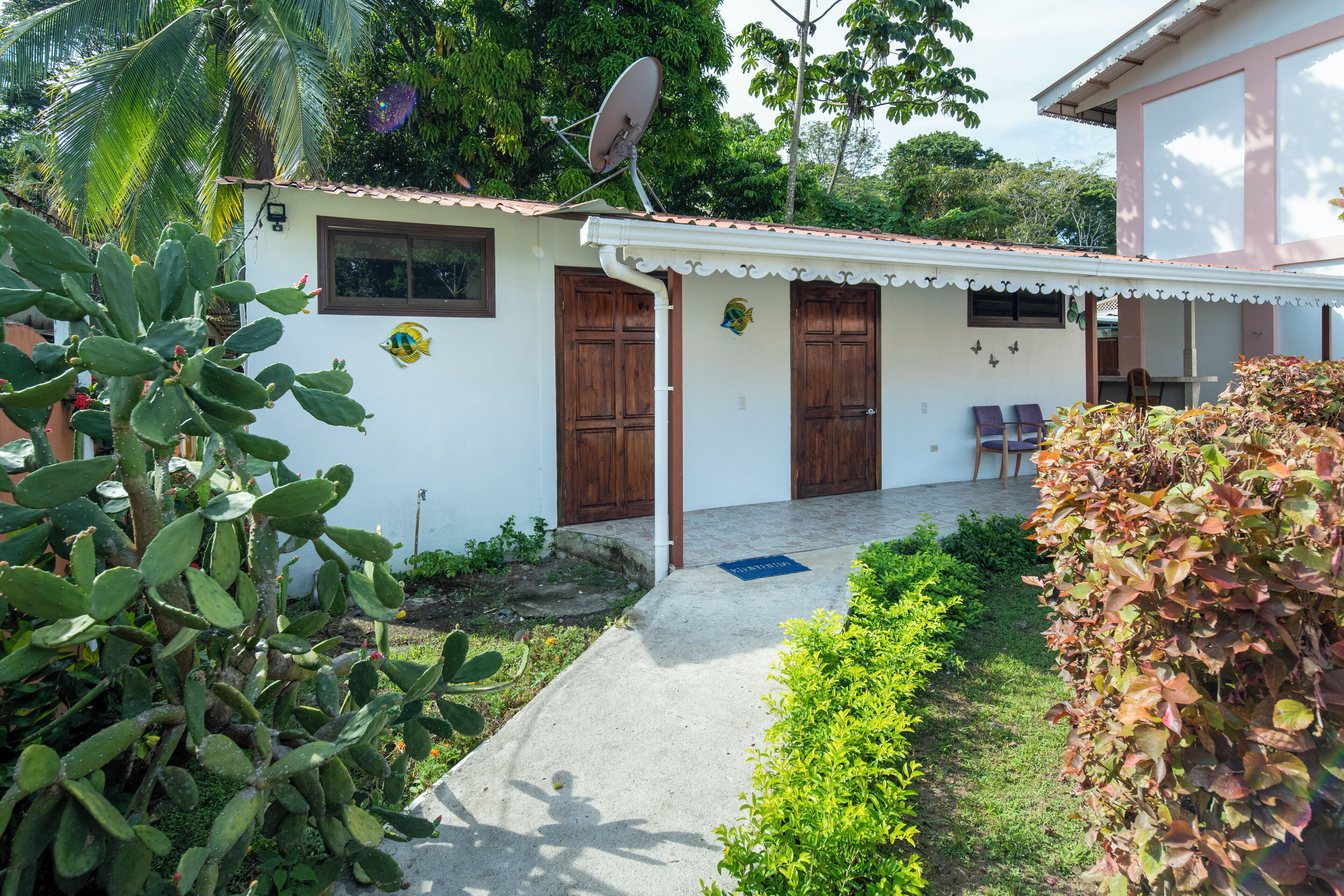 Una casa con antenna parabolica, porte in legno e un piccolo portico.