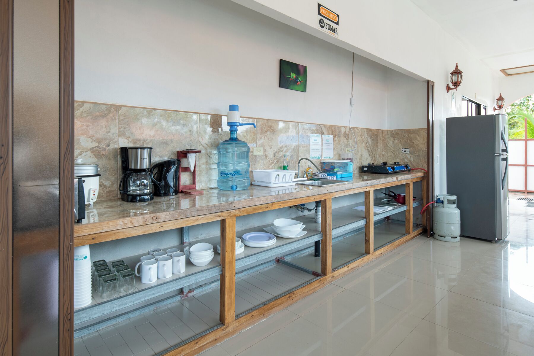 A modern kitchen with a marble backsplash, a coffee maker, a water dispenser, and a refrigerator.