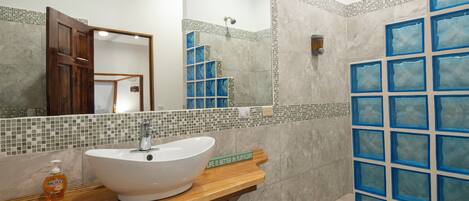 A bathroom with a white sink, wooden vanity, and a large mirror.