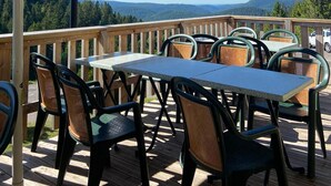 Una terraza con asientos al aire libre, un paraguas grande y una vista panorámica de montañas.