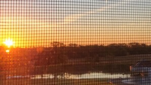 A sunset over a body of water with a fence in the foreground. - Foxy's Den cozy grain bin cabin with WiFi & AC in serene Kidder. Quiet & serene. (Kidder)