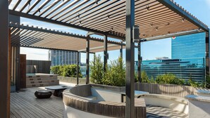 Una terraza en la azotea con cubierta de madera, zonas de estar y vistas al horizonte de la ciudad.