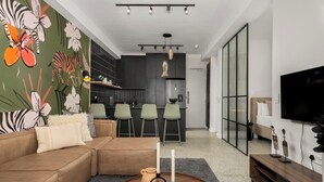 Una sala de estar moderna con un sofá modular, una mesa redonda de centro con velas, y un mural floral llamativo en la pared.