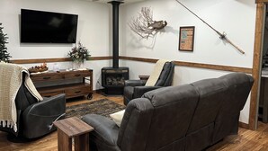 A living room with a fireplace, a sofa, a TV, and a ceiling fan.