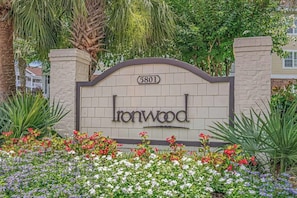 A gated entrance with a sign reading 'Ironwood 5801' surrounded by a garden with various flowers.