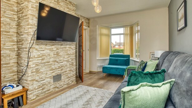 A living room with a stone wall, a grey sofa, and a teal armchair.