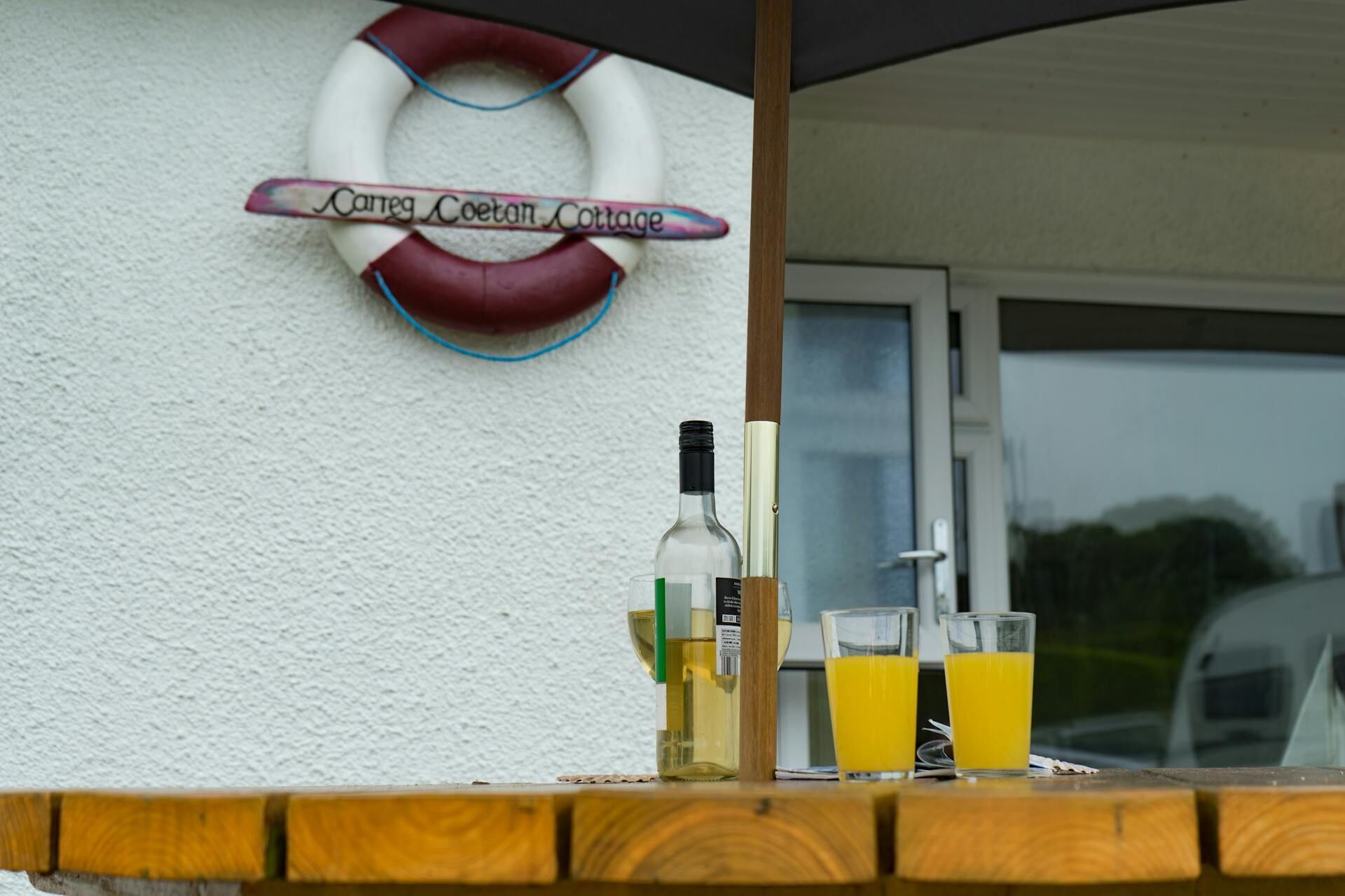 A bar area with a life preserver sign, a bottle of white wine, and glasses of orange juice.